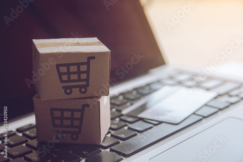 Shopping online concept - Shopping service on The online web. with payment by credit card and offers home delivery. parcel or Paper cartons with a shopping cart logo on a laptop keyboard