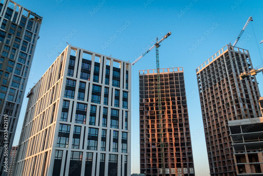 Construction site with reinforced concrete and brick buildings and cranes.