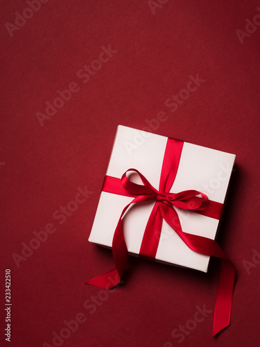 Top view of gift box with red ribbon over red background