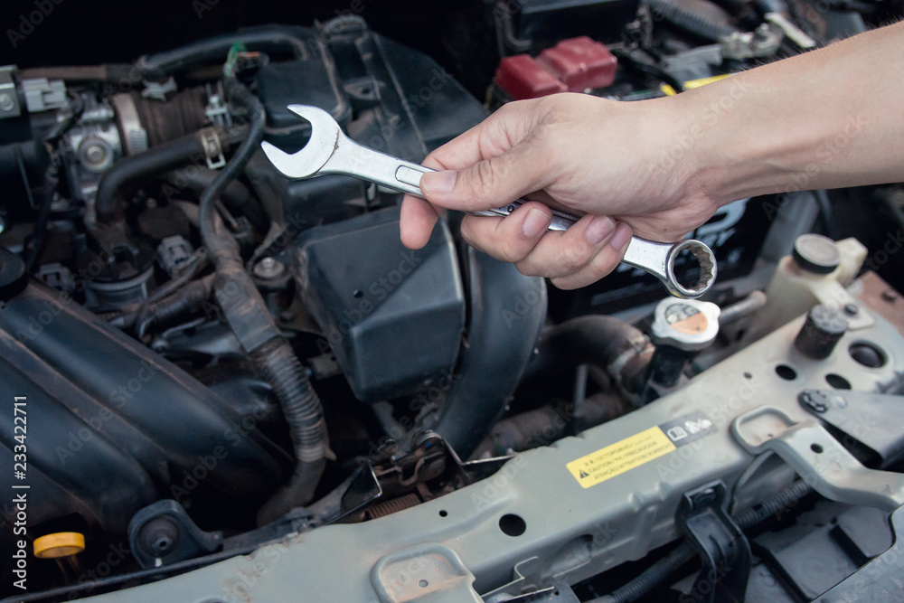 Car mechanic working with wrench in garage. Repair service.