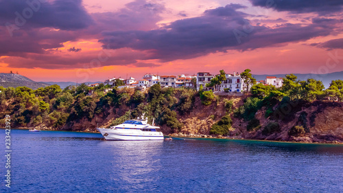 Sunset over Skiathos town, Greece. Luxury yacht in the bay of Skiathos, near the harbour