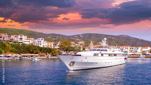 Sunset over Skiathos town, Greece. Luxury yacht in the bay of Skiathos, near the harbour photo