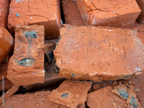 Red cracked brick of poor quality with black spots. Background, macro, new building material for construction