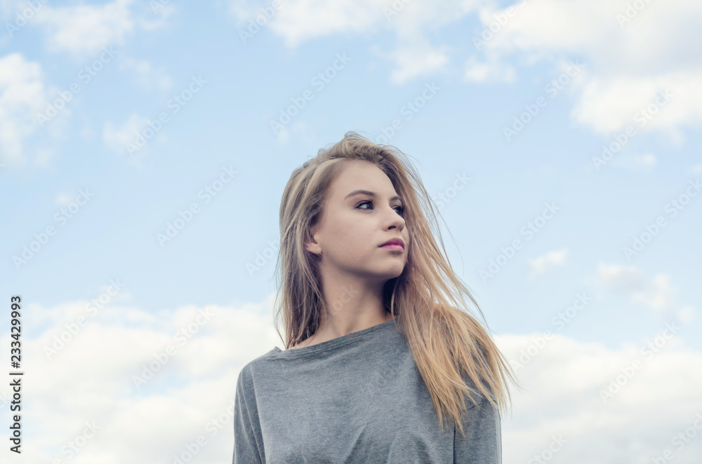Portrait of a beautiful girl on the background sky. Looks to the right. Youth culture. Fashion for young people. Freedom of choice. Portrait of a beautiful girl on the background sky. Looks to the right. Youth culture. Fashion for young people. Freedom of choice.