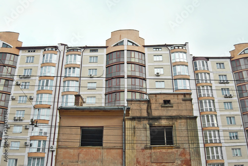 An old, dilapidated building on the background of a new building. Industrial demolition of the house. Concept: replacement of old housing with a new one.