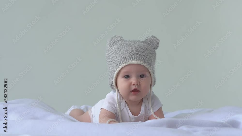 Happy baby girl . Child in hat laying on the bed and laughs. White background. 4K Happy baby girl . Child in hat laying on the bed and laughs. White background. 4K
