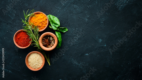 Fototapeta Naklejka Na Ścianę i Meble -  Colored spices on a black stone background. Free space for your text. Top view.