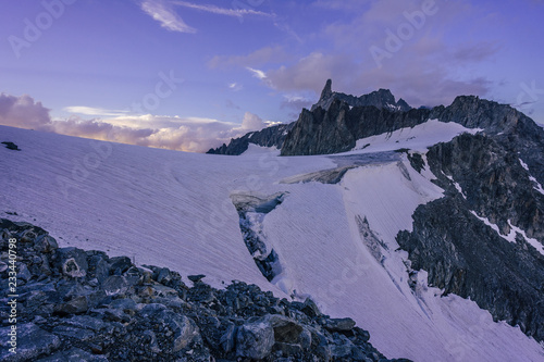 Stunning sunset view of an alpine landscape in Mont Blanc massif. Famous alpine peak Dent du Geant  Dente del Gigante  in purple evening colors. Alpinism and climbing on glacier in the Alps  Chamonix.