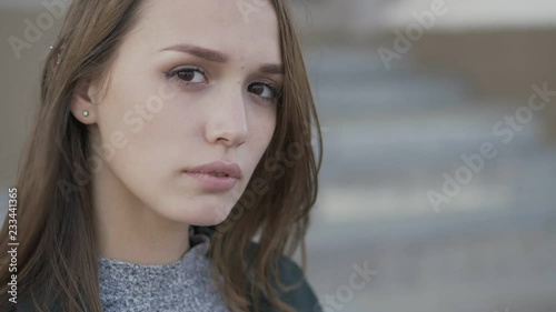 Extreme close up slow motion young stylish long hair brunette woman hair on the wind looking aside then into camera and sadly smiling