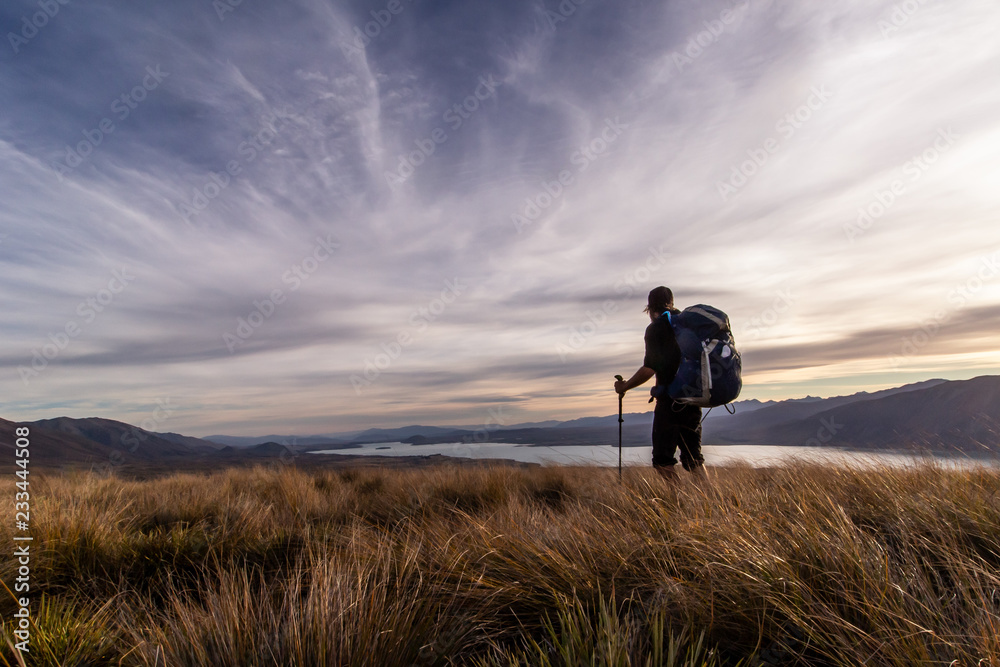 Silhouette of a hiker descending down from Stags Saddle in sunset, Lake Tekapo, New Zealand