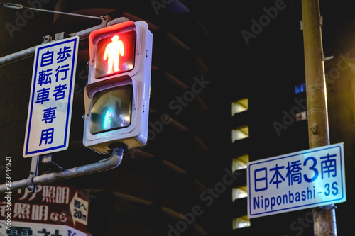 Traffic lights (red on) and traffic signs in japanese at Osaka, Japan in the night photo