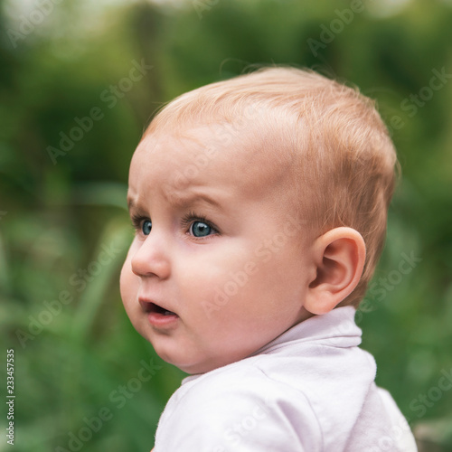 little blue-eyed child with blond hair looks very attentively and intently.