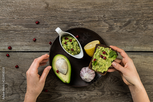 Photos Closeup top view of woman hands eating sandwich with guacamole sauce