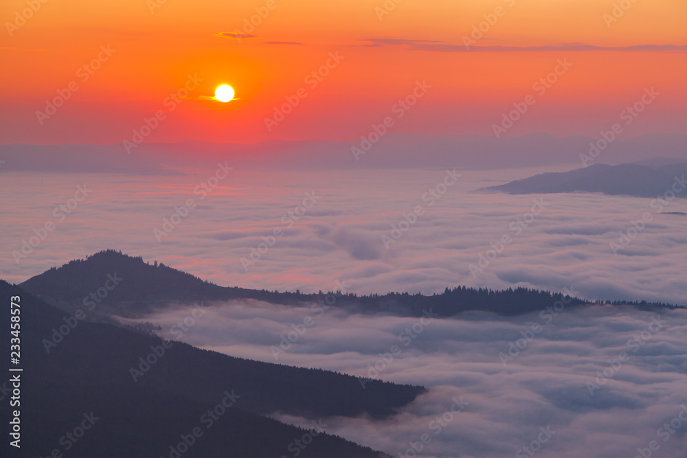 Golden hour in the mountains. Sunrise over mist-covered valley