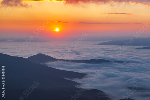 Sunrise over mist-covered valley. Golden hour in the mountains