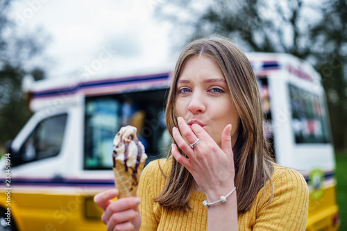 Young Adult Girl having ice cream and sucking fingers in Coventry, UK