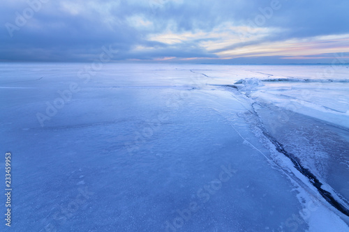 Fototapeta Naklejka Na Ścianę i Meble -  crack in the ice a cloudy sunset / winter landscape cloudy gloomy