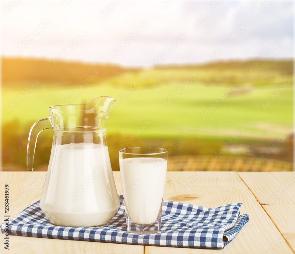Glass of milk and jug on blurred background Glass of milk and jug on blurred background