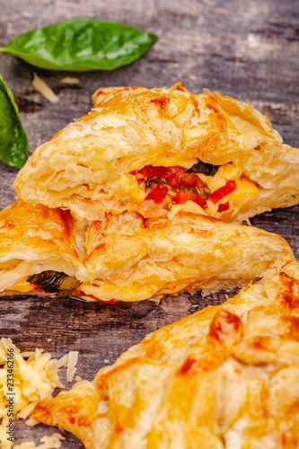 Puff pastry with cherry tomatoes, mozzarella cheese and basil on wooden rustic table. Close up