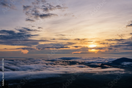 Beautiful nature landscape the sun is above the sea fog that covers the mountains and bright sky during sunrise in the winter at viewpoint of Phu Ruea National Park, Loei province, Thailand.