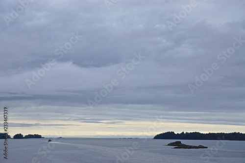 Sitka, Alaska, USA: Dawn on the horizon and thick clouds in the sky above the Eastern Channel, with islands and small boats in the distance.