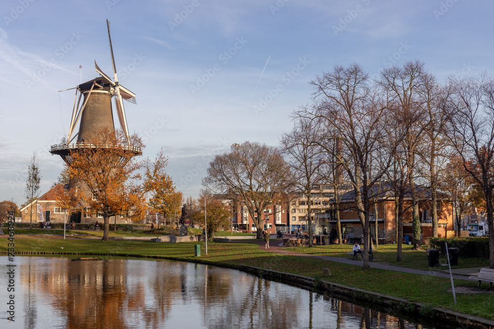 Windmill in urban neighbourhood in the Dutch city of Leiden on a clear day with a blue sky at sunset in autumn
