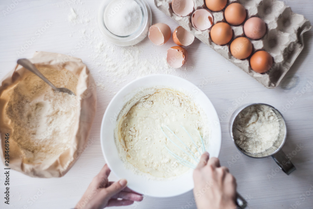 Process of making the dough, woman's hand whips eggs and flour in bowl Flat lay composition of ingredients and batter.selective focus Process of making the dough, woman's hand whips eggs and flour in bowl Flat lay composition of ingredients and batter.selective focus