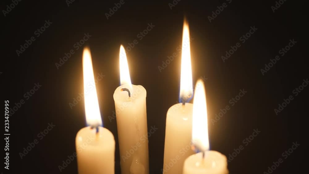Candles burning. Soft flames against dark black background. Shallow DOF. Focus on rear candle. Candles burning. Soft flames against dark black background. Shallow DOF. Focus on rear candle.