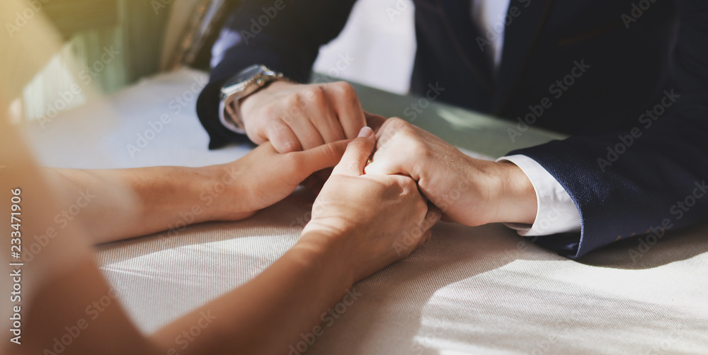 Fototapeta premium A couple is sitting in a cafe at the table. A man holds a girl's hand.
