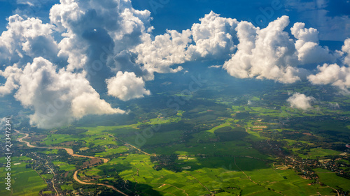 Sunbeam passing through the cloud over Chiangrai city with green grass field and mountain range. the areal shot has been taken through Airplane window.