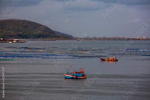 Fishing boat and transportation boat running in front of sea shell farm at Sriracha harbor Chonburi
