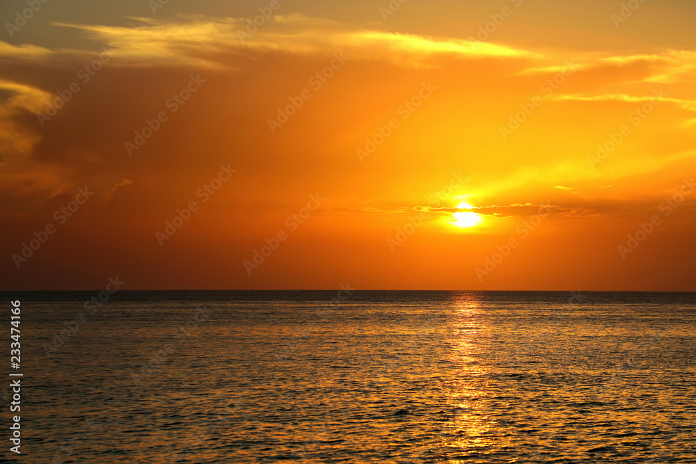 Colorful empty seascape with shiny sea over cloudy sky and sun during sunset in Cozumel, Mexico
