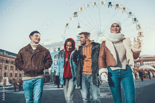 Φωτογραφία Low angle positive men talking with pleased women while walking together on stre