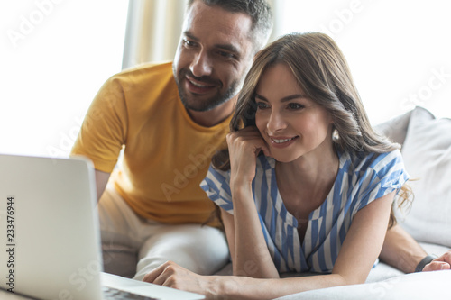 Beautiful woman and smiling man watching photos on laptop