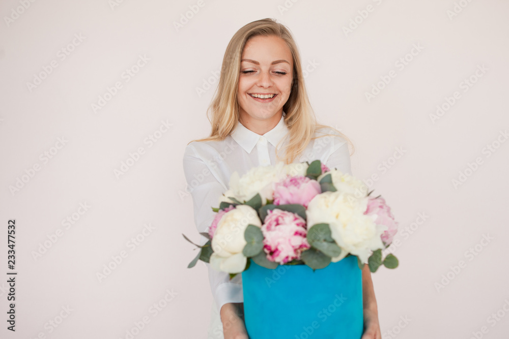 Woman with flowers in a hat box. Bouquet of peonies. Girl in business style, receives flowers or gives, Blue box.