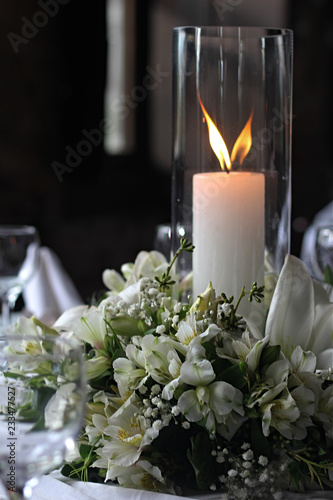 vela branca e grande, acesa em meio a arranjo floral centro de mesa em celebracao requintada