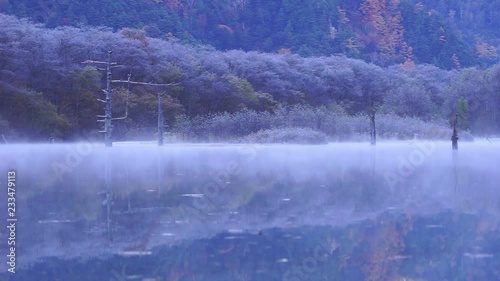 Beautiful Moving Morning Mist over Peaceful Pond Reflect Background of Autumn Forest Covered by First Snow in Kamikochi (Switzerland of Japan) in Nagano, Famous Tourist Destination in Japan
