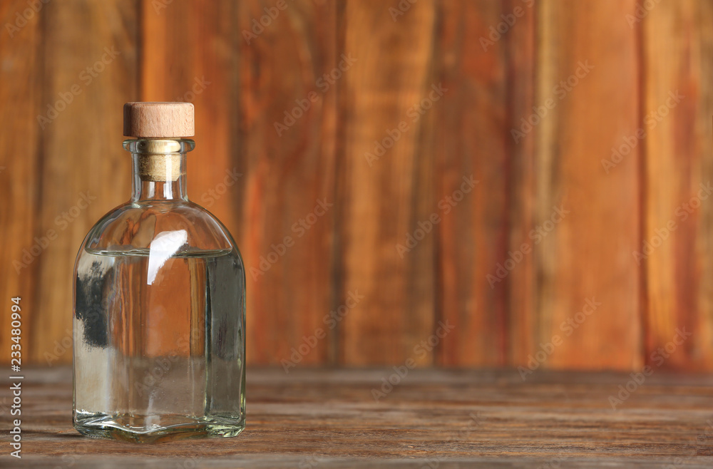 Glass bottle with vinegar on wooden background. Space for text Glass bottle with vinegar on wooden background. Space for text