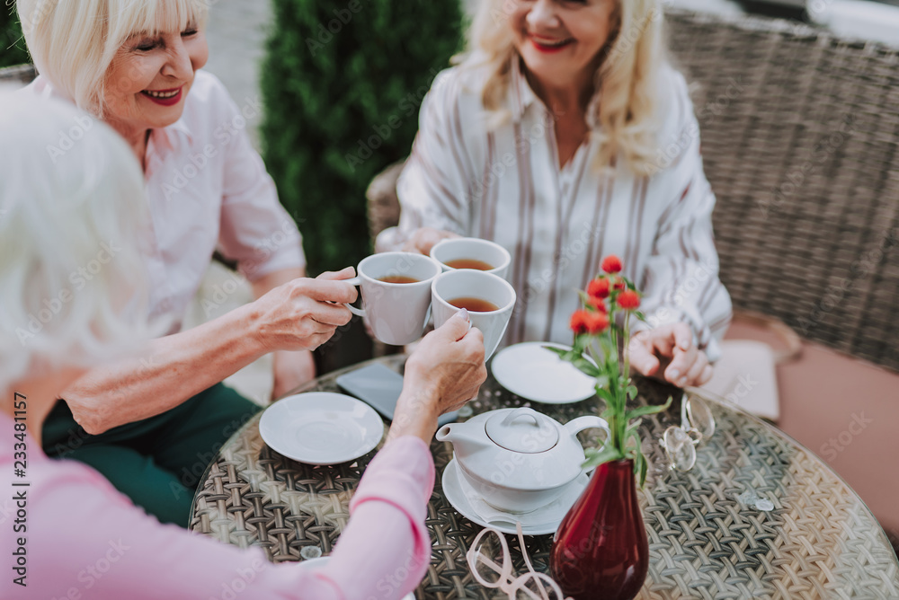Happy older smiling ladies holding cups with tea outdoor Happy older smiling ladies holding cups with tea outdoor