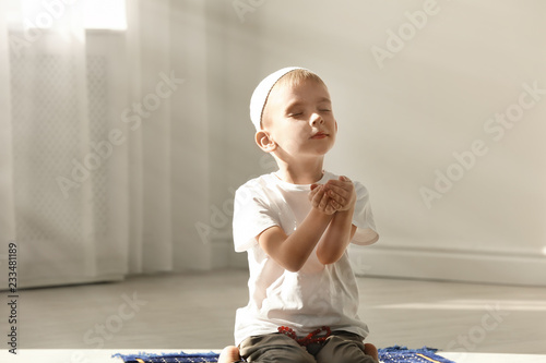 Little Muslim boy with misbaha praying indoors