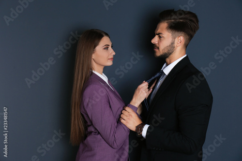 Woman molesting her male colleague on dark background. Sexual harassment at work