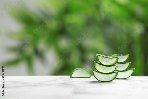 Slices of aloe vera on table against blurred background. Space for text