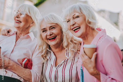 Waist up portrait of three positive older women joking and having fun together