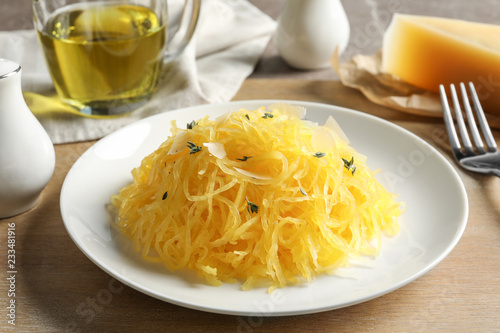 Plate with cooked spaghetti squash on wooden board