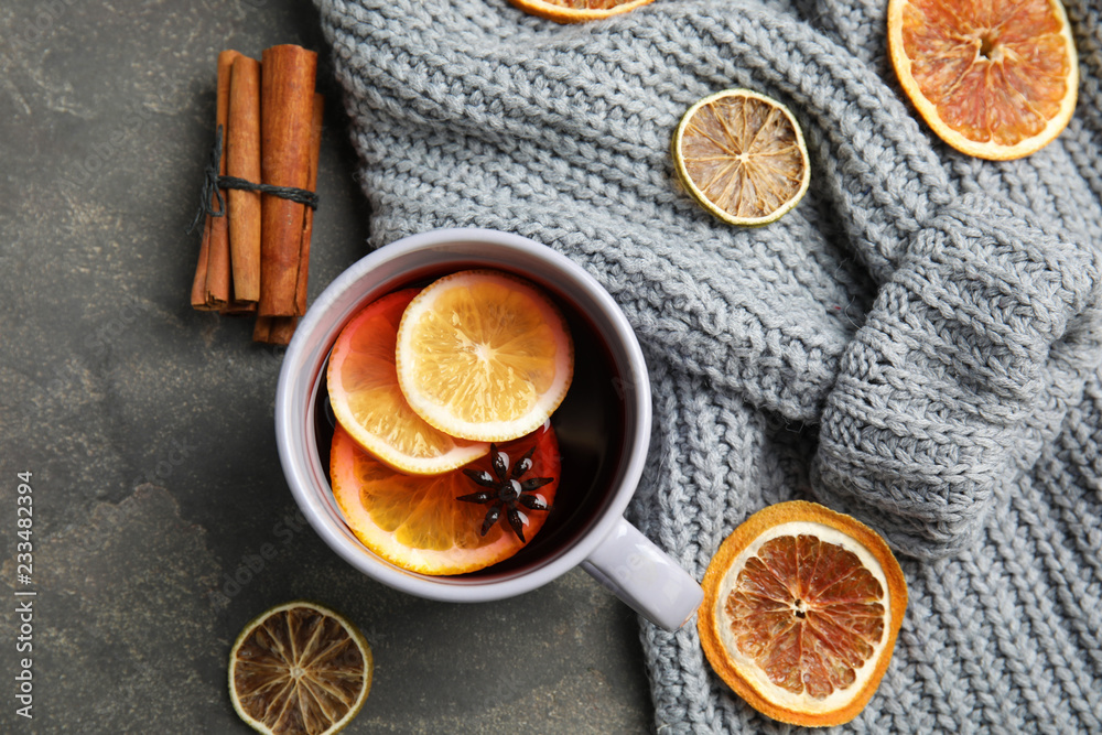 Flat lay composition with cup of hot winter drink and warm knitted sweater on gray background. Cozy season Flat lay composition with cup of hot winter drink and warm knitted sweater on gray background. Cozy season