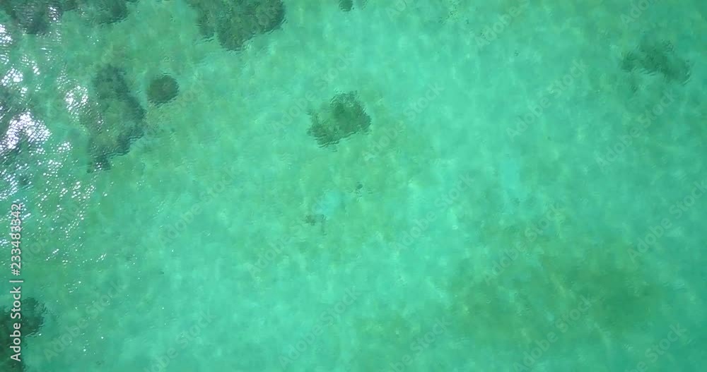 Ascending aerial drone camera down view over beautiful emerald green shallow sea water slow zoom out revealing tropical coral reefs in Thailand. 4k 1.9:1 23.976fps