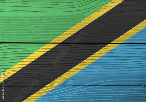 Flag of Tanzania on wooden plate background. Grunge Tanzanian flag texture, A yellow-edged black diagonal band: the upper triangle is green and the lower triangle is blue.