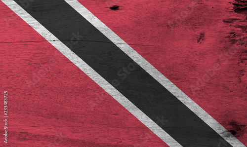 Flag of Trinidad and Tobago on wooden plate background. Grunge Trinidadian flag texture, A red field with a white-edged black diagonal band. © Achisatha