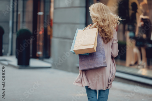 I am heading to the store. Back view portrait of middle-aged woman carrying colorful shopping bags photo