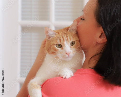 White-red cat put his paws on the woman's shoulder close-up rear view